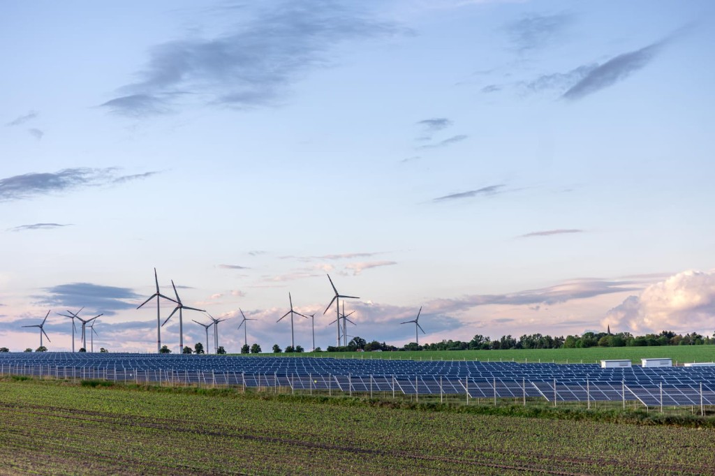 Solar farm with wind turbines at golden hour — hybrid renewable generation
